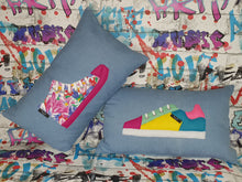 Load image into Gallery viewer, hazeldee Home Handmade bold colour-block trainer cushion, rectangular bolster shape with real laces trim on a blue denim base.  A great conversational trainer cushion for kids and grown ups alike!  Bring some fun and colour into your space with this handmade cushion with a trainer with laces detail!  Colour-block sneaker trainer cushion with Hazeldee Home label detail.  Approximately 12&quot; x 20&quot; (30cm x 50cm) with a zip opening.   Comes with a polycotton cushion inner.
