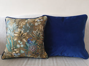 Hazeldee Home Handmade double-sided  cushion featuring an intricate jacquard pattern with peacocks, botanical green and yellow leaves at the front and a contrasting plain cobalt blue Italian cotton velvet on the reverse, piped with the same blue velvet.   Approximately 18" x 18" (45cm x 45cm) square with a concealed zip. 
